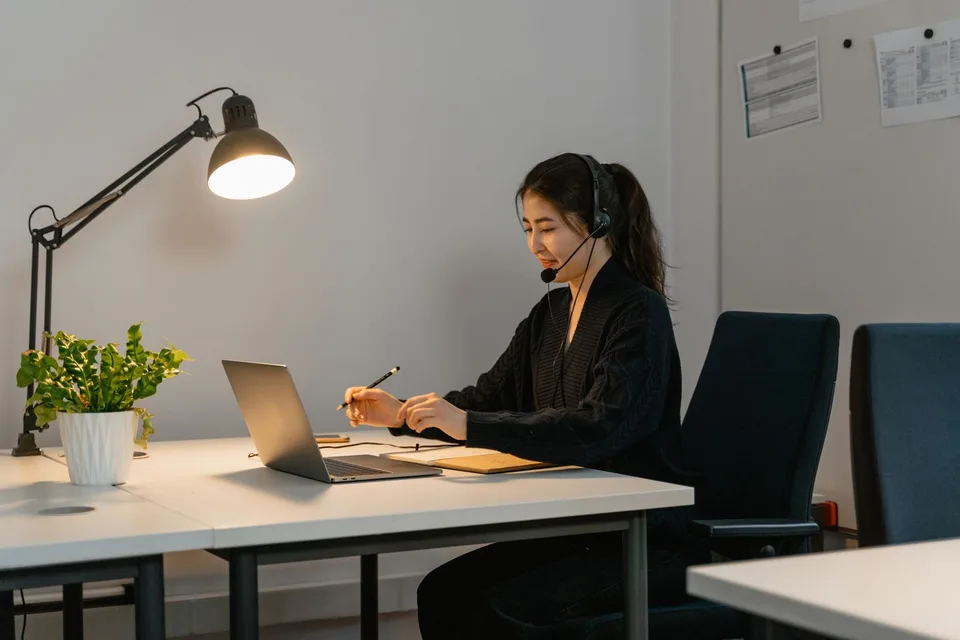 Profissional com headset atendendo pelo notebook em um escritório