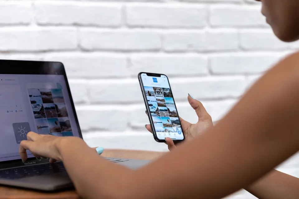 Profissional usando notebook e celular para trabalhar com conteúdo digital